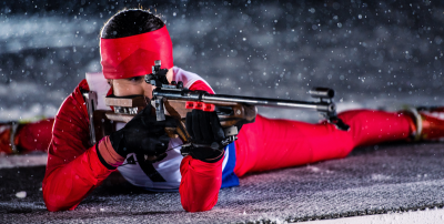 Grafika przedstawiająca kobietę strzelającą z broni uprawiająca biathlon